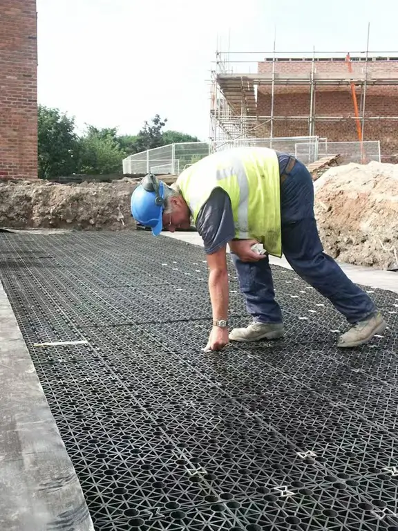 Contractor assembling interlocking shallow geocellular cells to form a sub-base stormwater attenuation bed under pavement for drainage and infiltration.