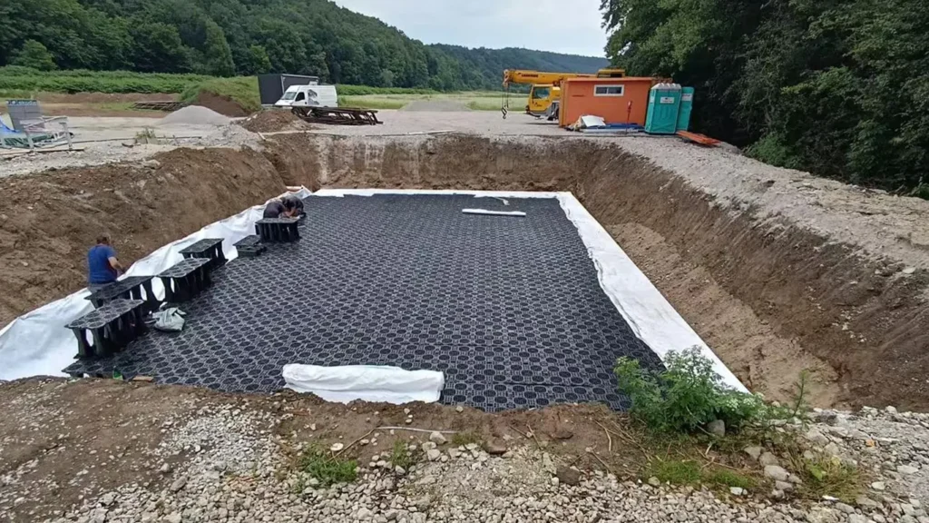 Laying geotextile and geomembrane liner for underground soakaway tank base preparation