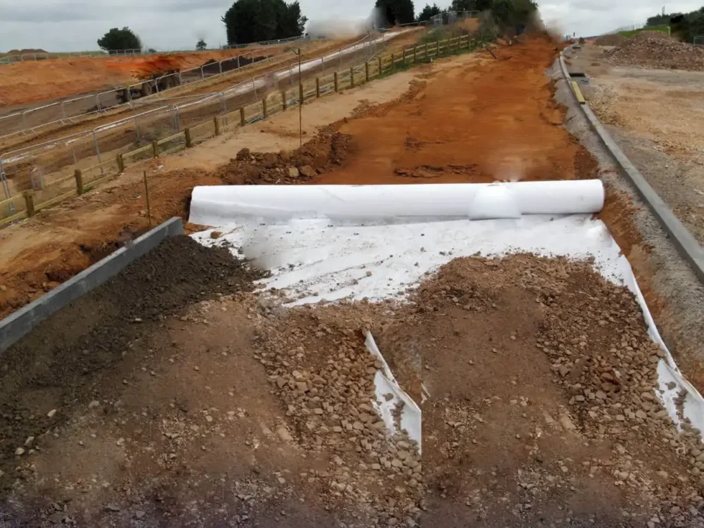 Woven geotextile reinforcement layer for railway ballast separation and ground improvement