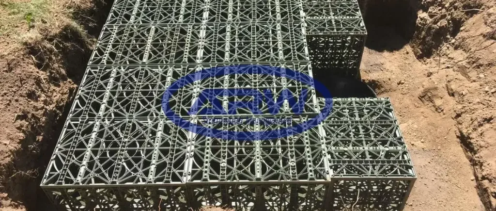 Backyard basin under construction in Canada—black geomembrane liner with nonwoven geotextile; worker bedding a perforated drain and catch-basin riser.