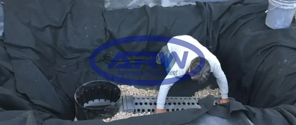 Backyard rock water feature with planting—pond liner edges visible during landscaping, accent lighting installed.