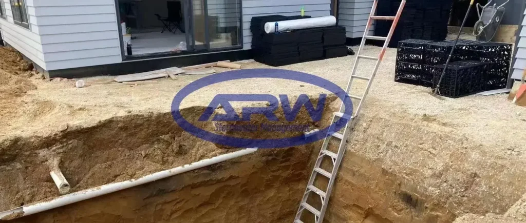 Australia/New Zealand residential OSD (on-site detention) bed—modular geocellular crates stacked and wrapped in white nonwoven geotextile for attenuation/infiltration.